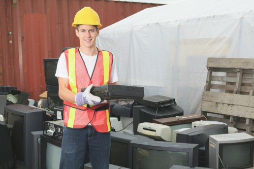 Worker wearing PPE and using a trolley for manual handling at a flat clearance